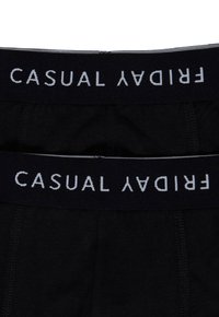 Sorte boxer briefs med en mørk elastisk linning, der har hvid tekst, som står "CASUAL FRIDAY." Glat tekstur og tætsiddende design.