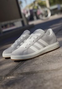 Šedé semišové tenisky s bílými koženými pruhy a tkaničkami, s texturovanou gumovou podrážkou a embosovaným logem na jazyku.