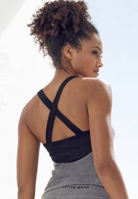 Gray activewear tank top with a black cross-back design. Features soft material and a fitted shape. Minimal branding on the lower edge.