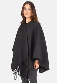 Schwarzer Poncho aus einem weichen, strukturierten Material, mit fransigen Kanten und einem lockeren, drapierten Design, das einfache Bewegungen ermöglicht.