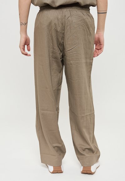 Pantaloni leggeri color khaki con vita elasticizzata e dettagli plissettati. Tessuto liscio con una vestibilità comoda, indossati con sneakers bianche.