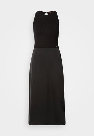 Abito nero con un corpino in maglia testurizzata e una gonna in satin liscia. Senza maniche, con una scollatura alta e un dettaglio a occhio di chiave sulla schiena.