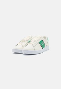Valged laced-sneakerid, millel on roheline aktsentriba, sile nahk, kummist talla ning minimalistlik disain kontrastsete õmblustega.