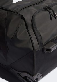 Borsa duffel nera realizzata in tessuto resistente, con cerniere, forma strutturata, dettagli in rete e una base robusta con manici integrati.