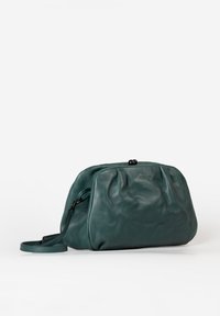 Türkise Lederhandtasche mit glatter Textur, runder Form, Reißverschluss und abnehmbarem Tragegurt. Verfügt über sanfte Falten und dezente Markenkennzeichnung.