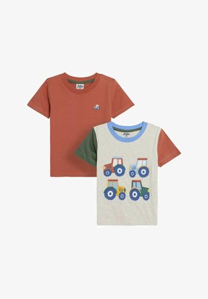 Conjunto de dos camisetas para niños. Una es de color óxido con un pequeño motivo de tractor azul; la otra es de color gris claro con gráficos de tractores coloridos.