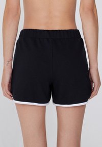 Schwarze Shorts mit weicher Textur, elastischem Bund und weißem Saum. Einfaches, funktionales Design ohne Taschen.