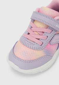 Baskets avec une tige synthétique violette, un motif en mesh pastel texturé, des lacets roses et une semelle en caoutchouc blanche. Bride ajustable pour un meilleur ajustement.