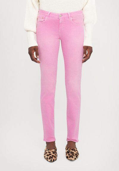 Lyserøde tætsiddende jeans med en glat tekstur, der har en midt-høj talje og klassisk fem-lomme design, parret med slippers i leopardprint.