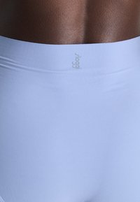 Leggings ușor albastre, cu talie înaltă, fără cusături, care prezintă o textură netedă și o branding subtilă la talie, ideale pentru confort și flexibilitate.