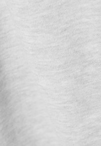 Κοντινή λήψη γκρι ανοιχτού υφάσματος που δείχνει απαλή, λεπτή υφαντική υφή με διακριτικές διακυμάνσεις στην πυκνότητα του νήματος και στις αποχρώσεις.