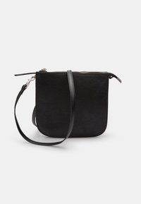 Črna crossbody torba z teksturirano površino, zadrgo in tankim usnjeni trak. Ima zaobljene robove in srebrno zadrgo.