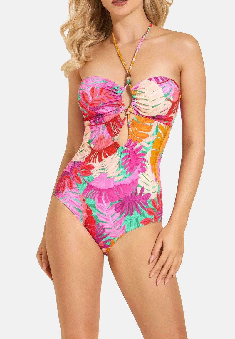 Kolorowy jednoczęściowy strój kąpielowy w stylu bandeau, z wycięciami i intensywnymi wzorami tropikalnych liści w odcieniach różu, zieleni i pomarańczy.