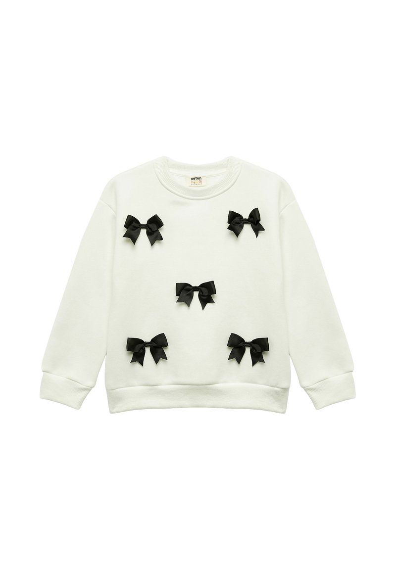 Sudadera blanca hecha de una tela suave, con varios lazos de cinta negra cosidos en la parte delantera, cuello redondo y puños acanalados.