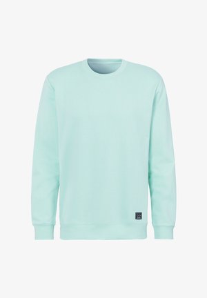 Light blue long-sleeve crewneck sweatshirt with ribbed cuffs and hem, featuring a small black rectangular logo patch near the bottom hem.