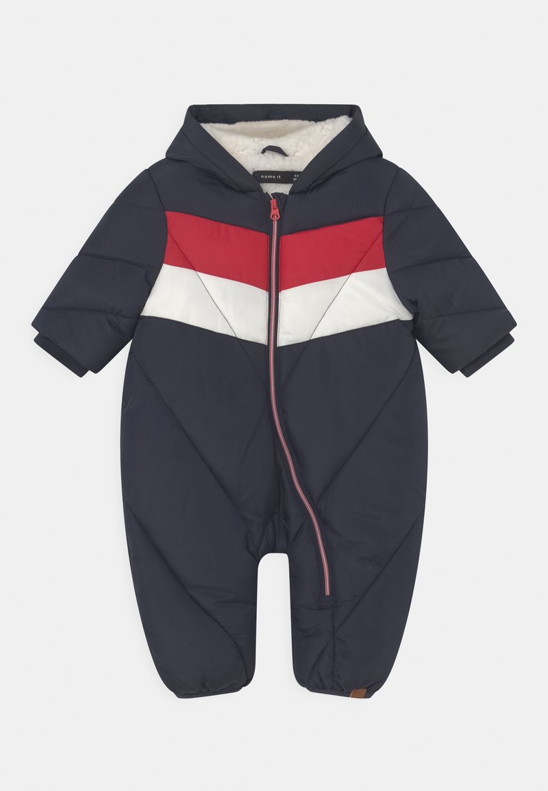 Combinaison de neige bébé bleu marine avec capuche, bande chevron rouge et blanche sur la poitrine, fermeture éclair à l'avant et doublure en polaire isolante.