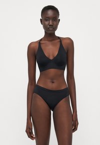Black lingerie set featuring a bralette with scalloped edges and matching high-waisted briefs, smooth texture, and a minimalist design.
