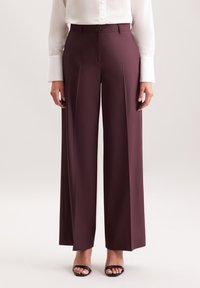 Bordeaux wijde broek met een getailleerde pasvorm, vervaardigd uit een soepele stof. Beschikt over een vlakke voorkant en verticale plooien voor een verlengde silhouet.