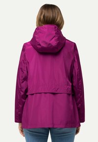 Fuchsia vattentät jacka med huva, har en insvängd midja, slät yta och lös passform. Synliga sömmar och en lagerdesign på baksidan.