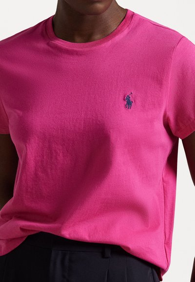 Kurzarm-Pink-Cotton-T-Shirt mit einem navyblauen gestickten Logo auf der linken Brust, rundem Ausschnitt und lockerer Passform.