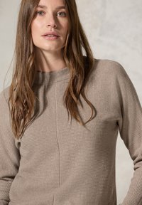 Maglione beige con texture, collo alto e maniche lunghe. Presenta dettagli di cucitura verticale. Tessuto morbido e intrecciato con una vestibilità comoda.