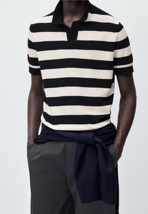 Black and cream striped polo shirt with a collar, short sleeves, and a textured knit. A navy sweater is casually tied around the waist.