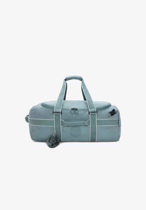 Sac de sport teal avec courtes poignées, fermeture zippée et accents blancs. Présente un logo rond et un porte-clés avec pompon détachable.