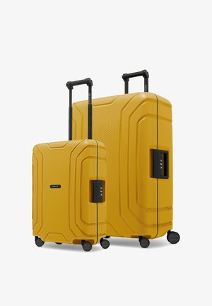 Deux valises rigides jaunes verticales avec surfaces texturées, poignées télescopiques noires, serrures à combinaison intégrées et quatre roulettes pivotantes chacune.