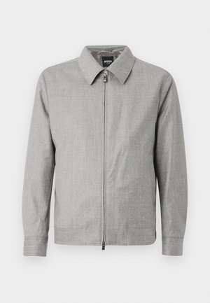 Graue Jacke mit einem kragenförmigen Ausschnitt, durchgehendem Reißverschluss und langen Ärmeln. Glatte Textur mit einem subtilen Muster während.