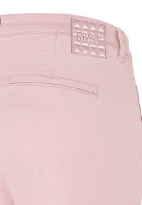 Pantalon rose clair vue de dos montrant une poche passepoilée unique et un patch de marque rose brodé portant l'inscription "MAC" près de la taille.