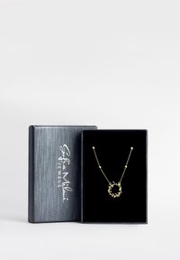 Guldhalskæde med en cirkulær vedhæng, der har et bladdesign, indeni en sort smykkeboks med et sølvlogo. Kæden indeholder små perler.
