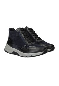 Zwarte en marineblauwe leren sneakers met zwarte veters, zijrits en dikke grijs- en zwarte rubberen zolen, onder een schuine hoek om beide schoenen te tonen.