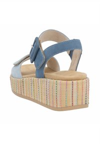 Sandalia de ante azul con una correa ancha y una hebilla decorativa, que presenta una suela de plataforma tejida texturizada y multicolor.
