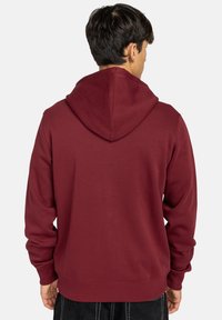 Bordeaux hoodie met een ontspannen pasvorm, zachte textuur, geribde manchetten en zoom. Grote capuchon met een naad die in het midden loopt.