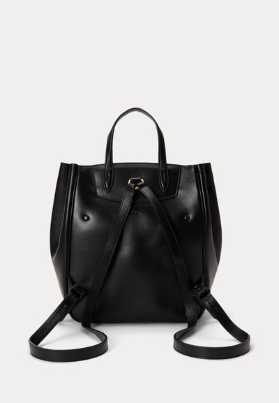 Μαύρο δερμάτινο σακίδιο με δύο λουριά ώμου και μια μικρή λαβή μεταφοράς, εμφανιζόμενο μπροστά σε απλό ανοιχτό φόντο.