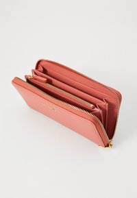 Roze leren portemonnee met gouden hardware, voorzien van een ritsluiting, meerdere vakken en een gestructureerde buitenkant.