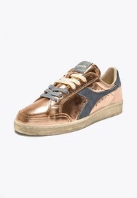 Sneaker in oro rosa metallizzato con dettagli in suede grigio, lacci piatti color beige e suola in gomma testurizzata. Presenta una punta arrotondata e perforazioni laterali.