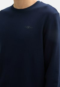 Marineblaues Rundhals-Sweatshirt aus weicher Baumwolle. Verfügt über ein kleines, tonales Logo mit "1962" auf der Brust. Regelmäßige Passform mit langen Ärmeln.