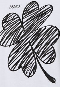 Camicia in tessuto bianco con una grande grafica nera di un trifoglio scarabocchiato con dettagli testurizzati, etichettata "LIU JO" sopra il disegno.