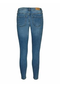 Skinny blue denim jeans with a mid-rise waist, two back pockets, and a smooth texture. Features a tan brand label on the waistband.