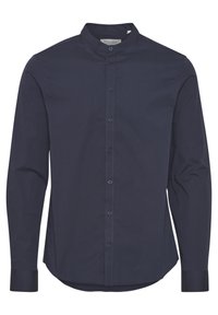Camisa de botón marina con cuello alzado, mangas largas y una textura suave. Presenta una tapeta frontal con botones a juego y un dobladillo recto.