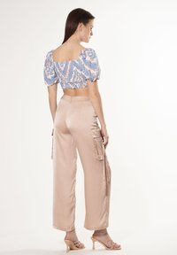 Blauwe gebloemde cropped blouse met pofmouwen, gecombineerd met lichtroze satijnen cargobroek. Bevat cargozakken en heeft een strakke pasvorm.