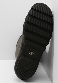 Sola de bota de borracha preta com padrão de textura e etiqueta de tamanho em relevo a dizer "8." Design limpo com um acabamento que melhora a aderência.