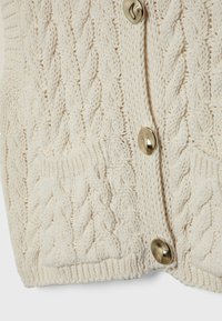 Crème-kleurige kabelgebreide cardigan met voorzakken en drie glanzende gouden knopen in het midden.