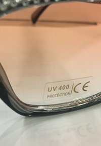 Sluneční brýle s UV 400 ochranou. Černý rám s lesklým povrchem a metalickým akcentem podél okraje. Skla mají jemné zabarvení.