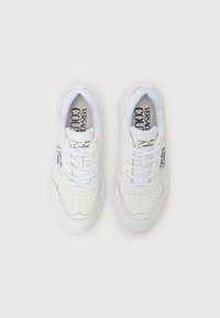 White sneakers with a smooth leather upper, perforated detailing, round toe, and thick translucent sole. Branding on tongue and side.