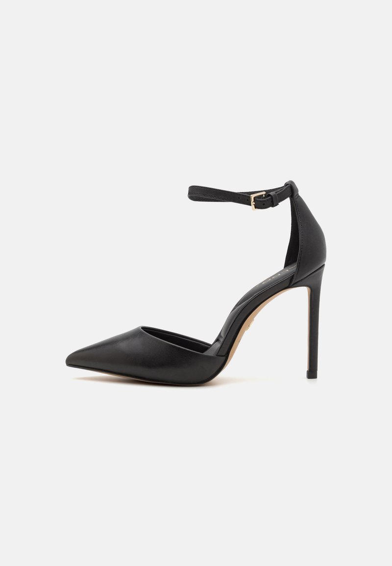 Juodas odinis aukštakulnis batelis su smailiu pirštu ir kulkšnies dirželiu. Yra stileto kulnas ir glotni tekstūra. Paprastas dizainas su auksinėmis detalėmis.