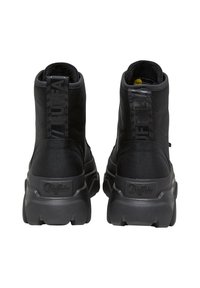Black ankle boots made of textured synthetic material, featuring a chunky sole, prominent branding, and a pull tab at the back for easy wear.