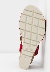Semelle crème d’une sandale rouge avec des rainures profondes, taille 4½ indiquée, affichant la marque « Gabor » et le texte « Made in Portugal ».