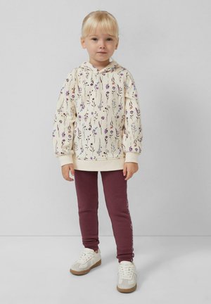 Felpa leggera color crema con motivo floreale, polsini a costine, abbinata a leggings color marsala. Sneakers bianche con accenti beige completano l'outfit.